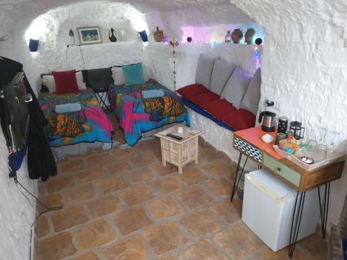 a room with two beds and a table in a cave at The Cave of Dreams in Baza