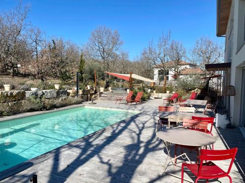 a patio with a table and chairs next to a pool at Maison d'Hôtes de Charme Le Clos de la Fontaine Piscine & SPA in Labastide-Marnhac