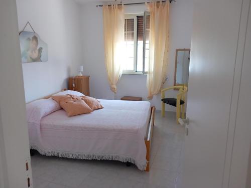 Il cappero, sul mare في بورتو باديسكو: غرفة نوم بيضاء بها سرير ونافذة