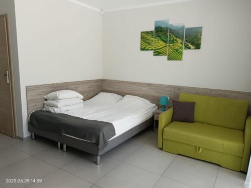 a bedroom with a bed and a green chair at Apartamenty Wilczyca in Wilczyn