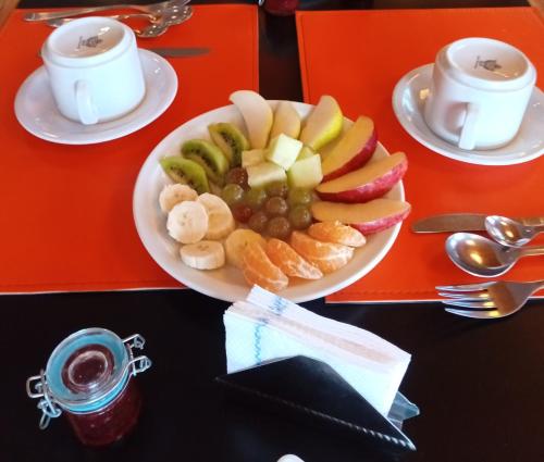 a plate of fruit on a table with two cups of coffee at Hotel Spa Nieves Del Cerro in Caviahue