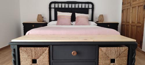 Schlafzimmer mit einem schwarzen Bett und rosa Kissen in der Unterkunft El Cantón in Bogarra