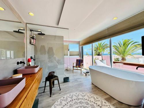 une salle de bain avec une grande baignoire et une grande fenêtre dans l'établissement Casa Color, à Corralejo