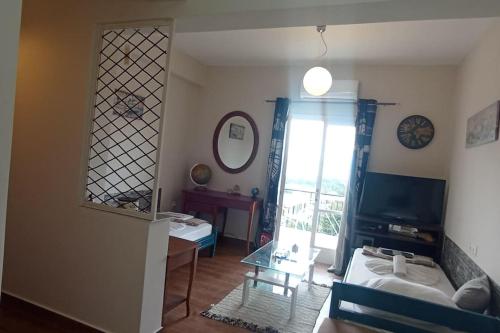 una stanza con un soggiorno con una finestra e una tv di Ipsos Apartment Mari a Città di Corfù