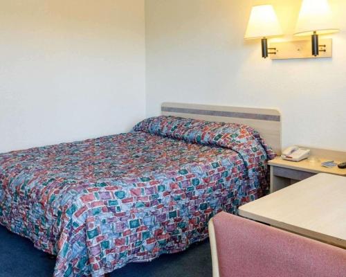 ein kleines Hotelzimmer mit einem Bett und einem Schreibtisch in der Unterkunft Loyalty Inn Columbus in Brice
