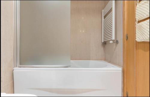 a white bath tub in a bathroom with a window at Deluxe Modern Flat w/ Balcony by Host Wise in Porto