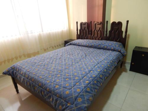 1 dormitorio con 1 cama con edredón azul y ventana en Ideal para descansar, en Ambato