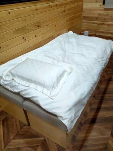 a bed with white sheets on it in a room at FUKUOKA FUKUTSU MUNAKATA YUSUKE HOUSE in Kōnominato