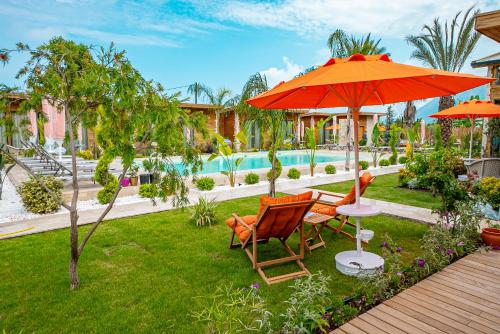 un patio con 2 sillas, una sombrilla y una piscina en Cirali Hestia Lodge, en Kemer