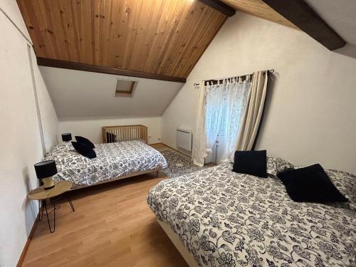 1 dormitorio con 2 camas y techo de madera en Gîte chaumière château de la Bouchatte en Chazemais