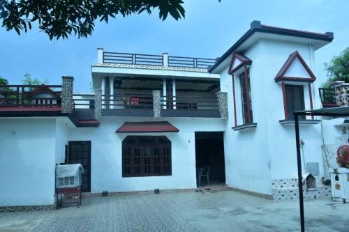 een wit huis met een balkon en een patio bij POP Sneha Homestay in Dhār Khurd