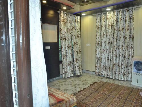 een kamer met gordijnen en een tapijt op de vloer bij POP Sneha Homestay in Dhār Khurd