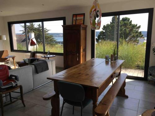 a living room with a wooden table and a large window at Chez Lorenz in Hôpital-Camfrout