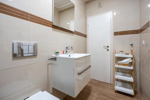 La salle de bains blanche est pourvue d'un lavabo et de toilettes. dans l'établissement Apartmani Mundo, à Ston