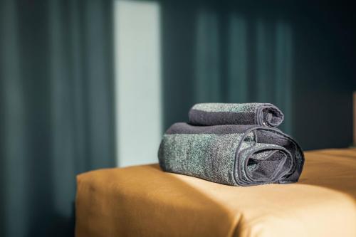 una pila de toallas sentadas encima de una cama en Luna Nova Rooms en San Valentino Torio