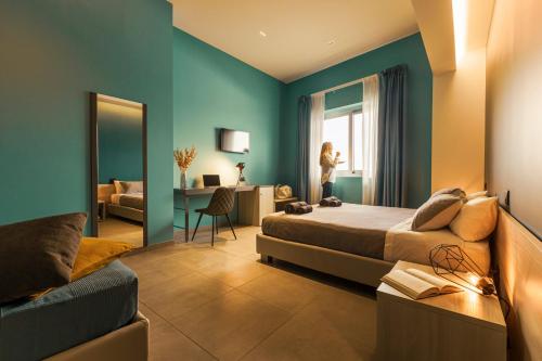 um quarto com uma cama e uma mulher de pé na janela em Luna Nova Rooms em San Valentino Torio