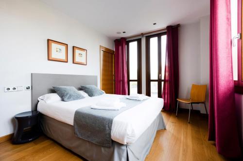 a bedroom with a large bed with red curtains at Guadalupe by Basquelidays in Hondarribia