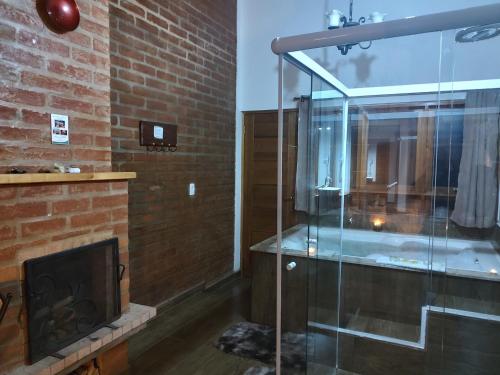 a bathroom with a glass shower and a fireplace at Colline Verte in Monte Verde