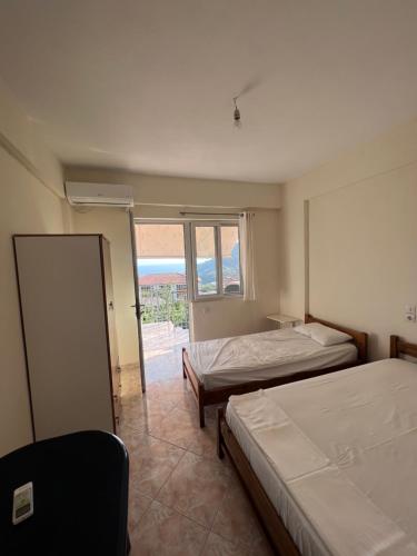 a bedroom with two beds and a large window at Dhoma Plazhi Husi in Himare