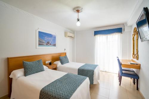 um quarto de hotel com duas camas e uma secretária em Hostal RR Feria by Beleret em Valência