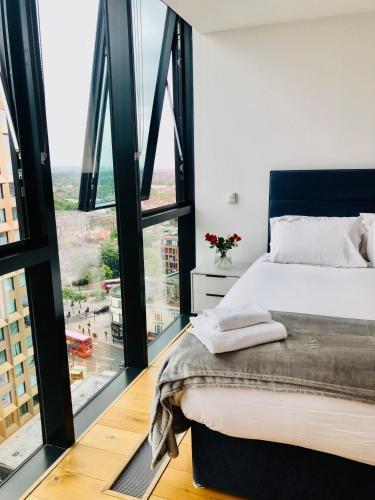 a bedroom with a bed and a large window at Luxury 2 bedroom apartment 20 min from central London in London