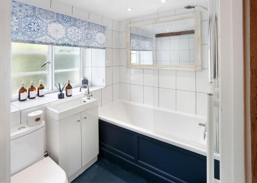uma casa de banho branca com uma banheira e um lavatório em Romantic Cotswold Cottage- dog friendly and village location em Mickleton