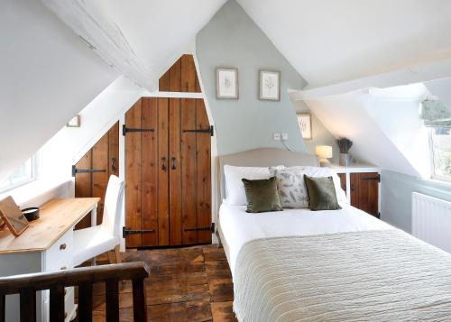 a bedroom with a white bed and a wooden desk at Romantic Cotswold Cottage- dog friendly and village location in Mickleton