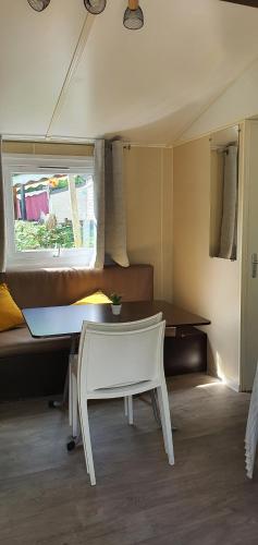 une table et une chaise dans une pièce avec une fenêtre dans l'établissement Mobil Home climatisé 6 personnes, à La Roque-dʼAnthéron