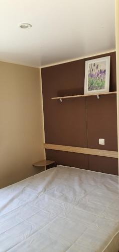 una camera da letto con un letto e un dipinto sul muro di Mobil Home climatisé 6 personnes a La Roque-dʼAnthéron