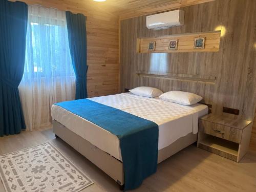 a bedroom with a bed with a blue and white comforter at Rüya Villen Park in Cıralı