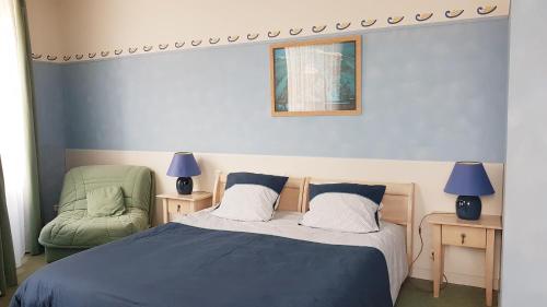 a bedroom with a bed and a green chair at Hôtel de la Presqu'ile in Crozon