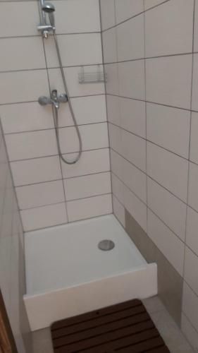 een badkamer met een douche en een witte tegelwand bij Hostel in picerija Špajza in Mojstrana