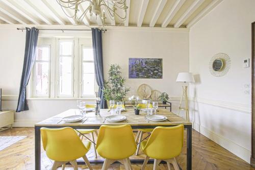 a dining room with a table and yellow chairs at La Villa Bligny in Étretat