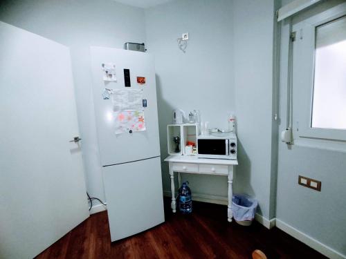 eine Küche mit einem Kühlschrank und einem Tisch mit einer Mikrowelle in der Unterkunft Darío Granada in Granada