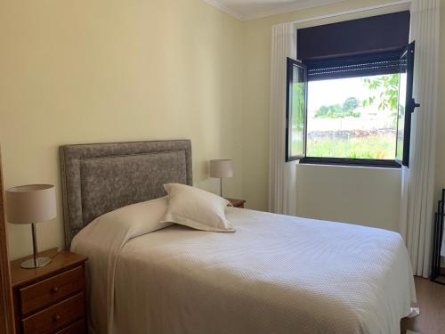 a bedroom with a white bed and a window at Casa Carvalhal do Esporão 