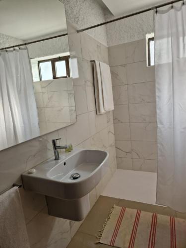 a white bathroom with a sink and a shower at Apartamentos Turísticos Clube Vale Leão in Figueira da Foz