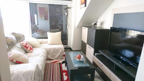 ein Wohnzimmer mit einem Sofa und einem Flachbild-TV in der Unterkunft Ático con piscina en palmeira in Ribeira