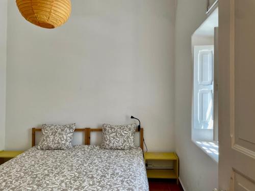 a bedroom with a bed with two pillows and a window at Julias Pateo in Carcavelos
