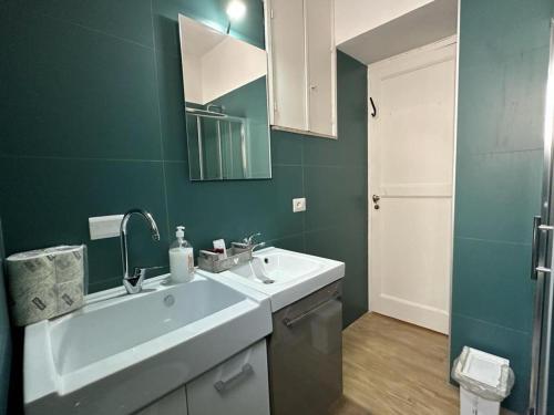 a bathroom with a white sink and a green wall at Olympus Pompei Rooms in Pompei