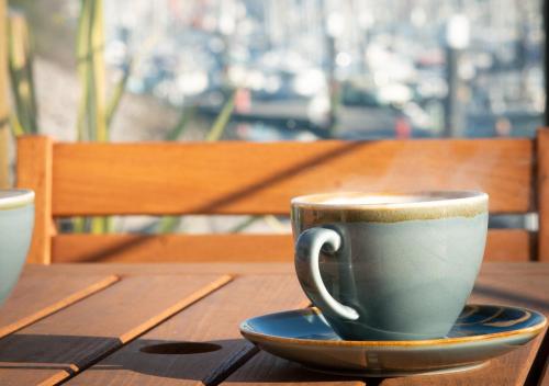 a cup of coffee sitting on a wooden table at Rooms at Haslar Marina in Gosport