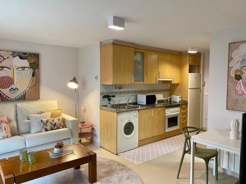 een woonkamer met een bank, een tafel en een keuken bij Andainas Apartamentos Turísticos F in Milladoiro