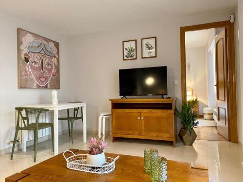 een woonkamer met een flatscreen-tv en een tafel bij Andainas Apartamentos Turísticos F in Milladoiro