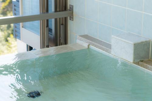 Atami-view Resort في أتامي: حوض استحمام مملوء بالماء بجوار مبنى