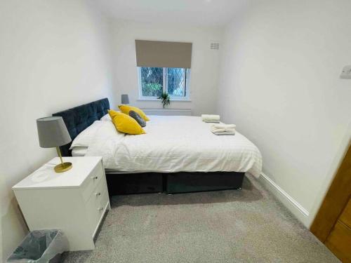 a bedroom with a bed with yellow pillows and a window at Modern cosy house /free parking for two cars/ 3 minutes walk to the underground in London