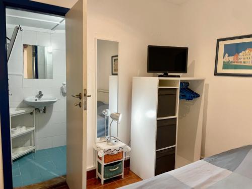 a bedroom with a television and a bathroom with a sink at Julias Pateo in Carcavelos