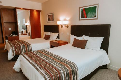 ein Hotelzimmer mit 2 Betten und einem Spiegel in der Unterkunft Howard Johnson Hotel Yerba Buena in Yerba Buena