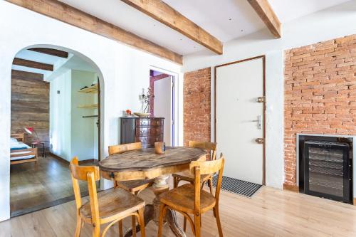 une salle à manger avec un mur en briques et une table et des chaises en bois dans l'établissement Bel appartement, proximité plages Mourillon, à Toulon