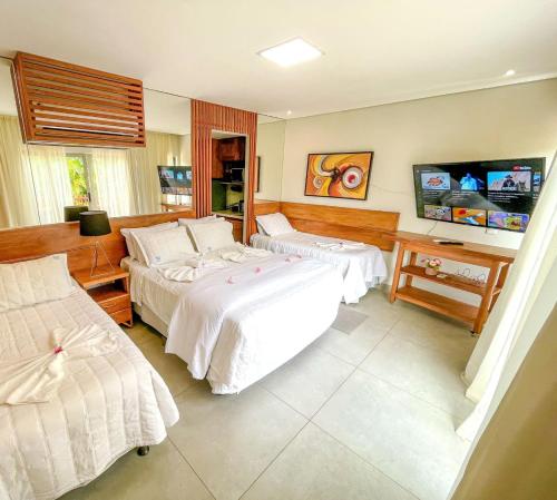 a hotel room with two beds and a television at Flat Completo Pipa no condominio do lle de Pipa in Pipa
