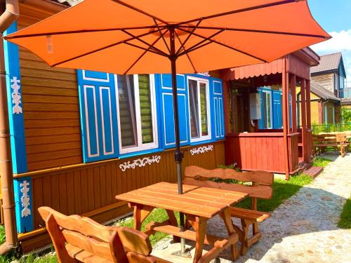 CHATA OTWARTYCH OKIENNIC Pokoje Gościnne في سوبراشل: طاولة خشبية مع مظلة أمام المنزل