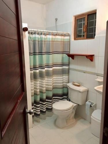 a bathroom with a toilet and a shower curtain at Casita Sac-Nicté in Mahahual